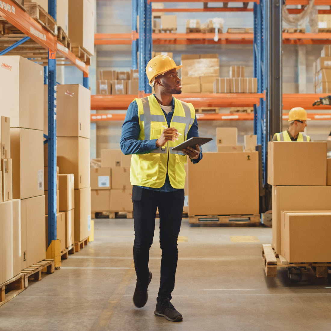 Worker in a warehouse with boxes and pallets